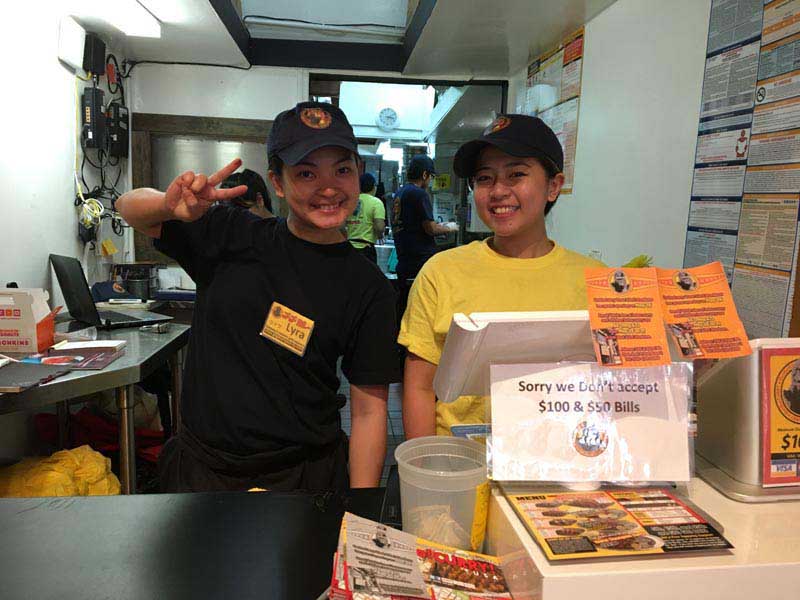 Two happy employees smile behind the counter at Go! Go! Curry!