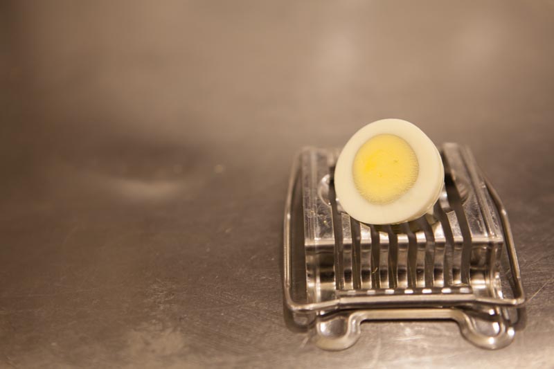 Premium boiled sliced egg on a counter with a slicer